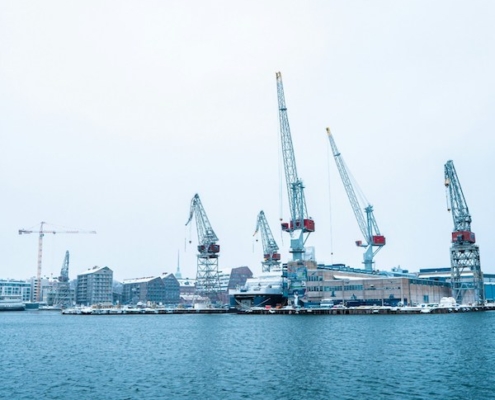 Laivanrakennustyömaa, jossa työntekijät käyttävät suojavarusteita ja noudattavat työturvallisuusohjeita.